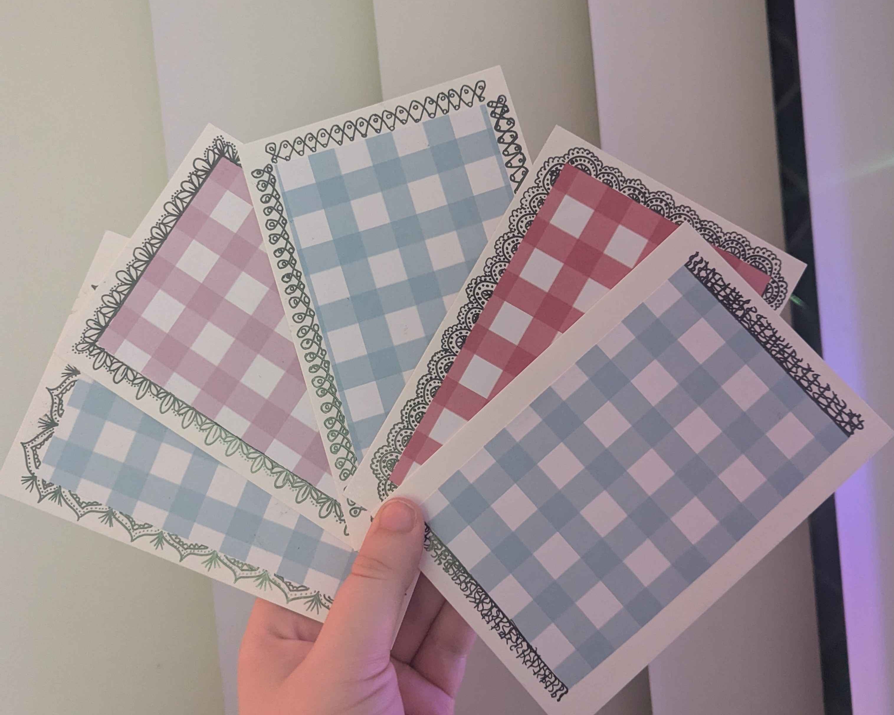 Hand holding four checkered paper sheets with a plain background