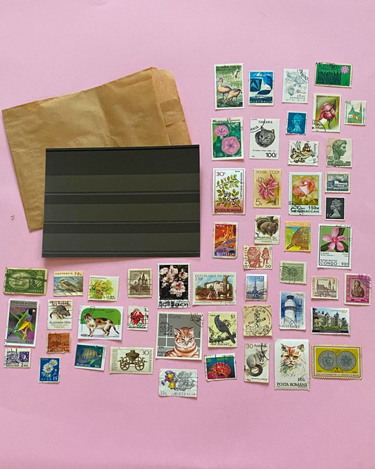 Collection of vintage stamps and a brown envelope on a pink background